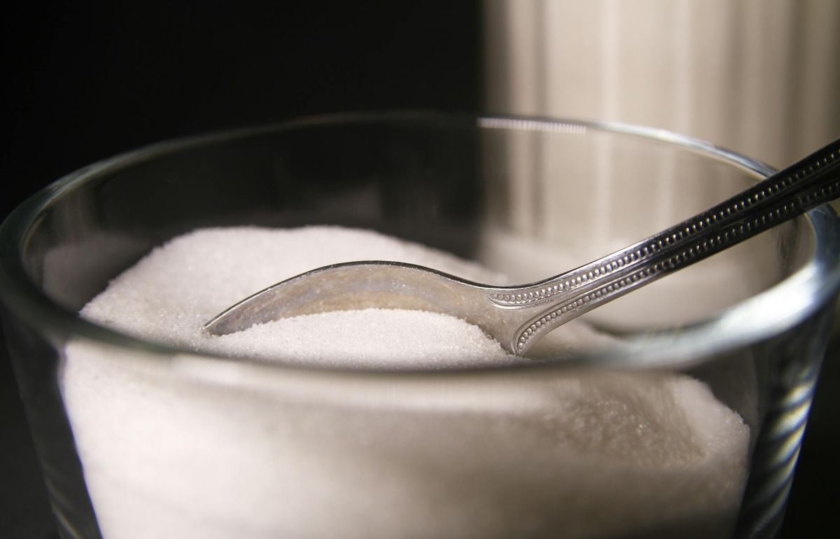 Granulated sugar in a glass bowl featuring a spoon.