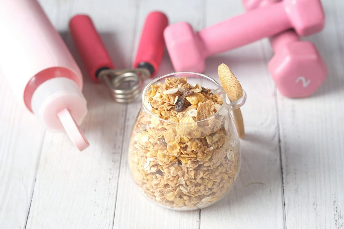 A glass jar of granola alongside pink dumbbells and a water bottle — the daily inputs that drive metabolic health.