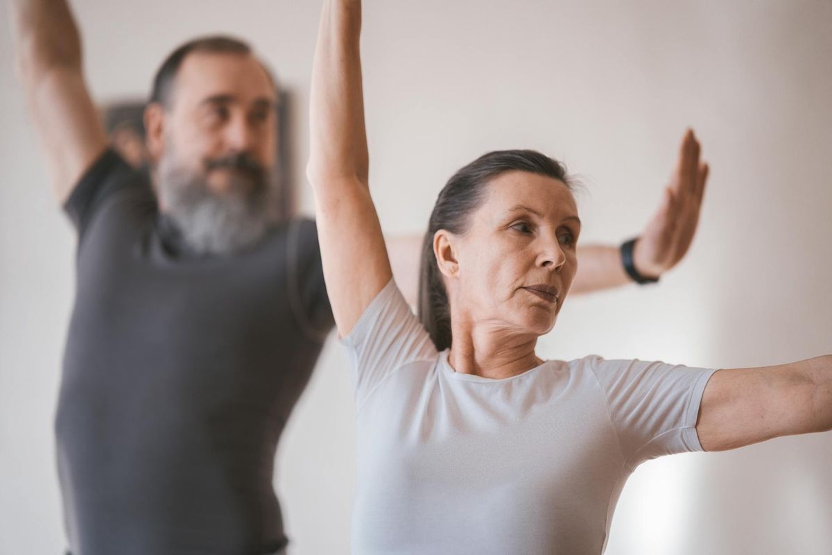 Senior adults in a yoga session indoors, focusing on stretching and balance.