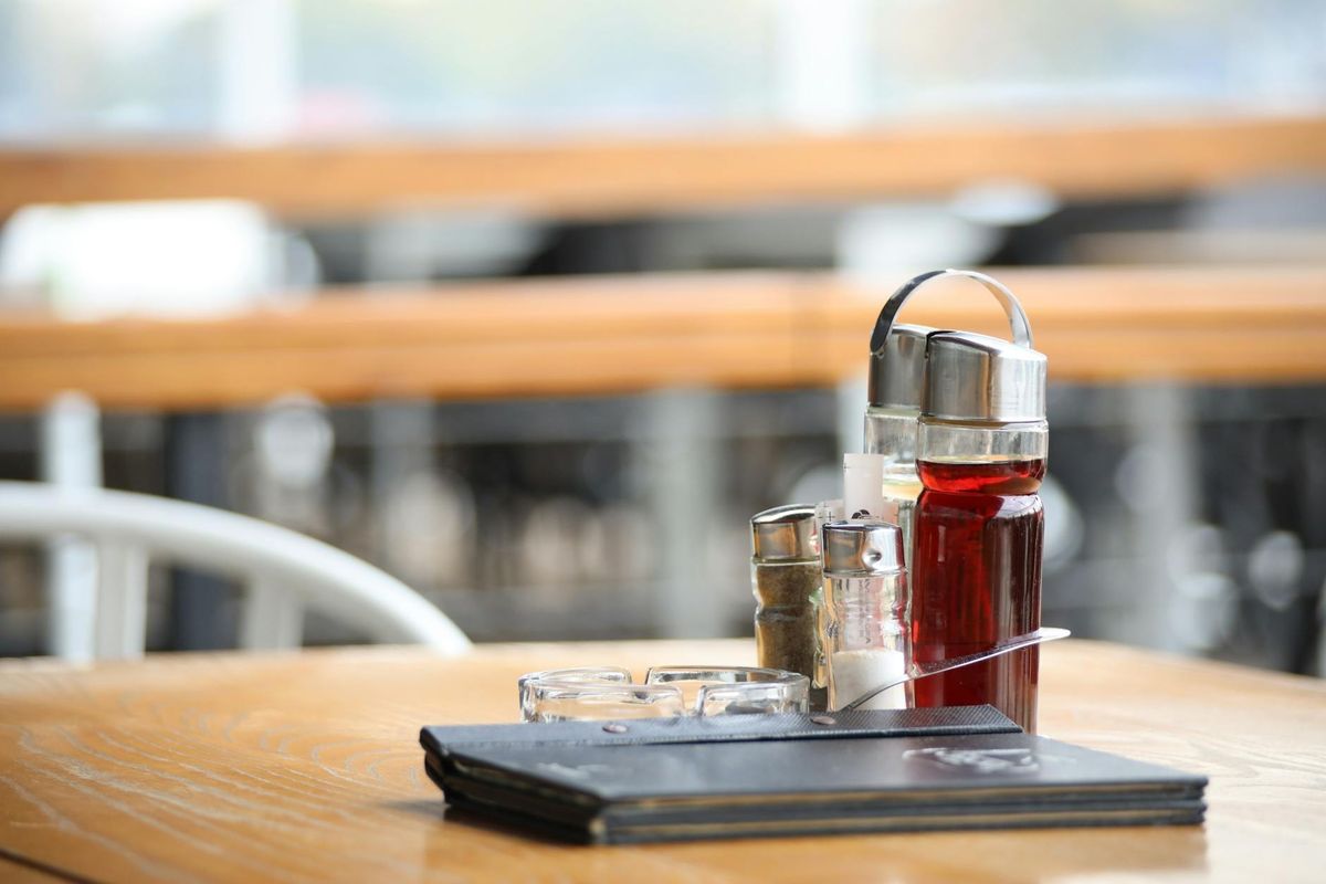 A restaurant table with condiments and a menu.