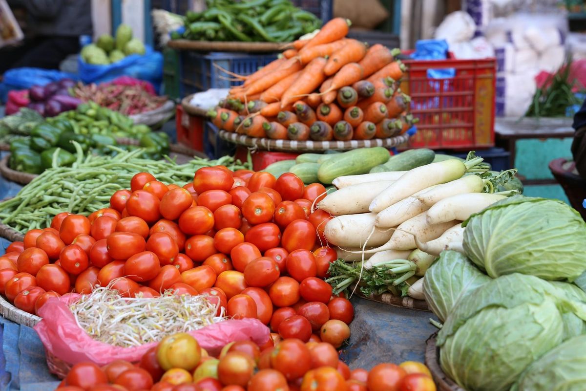 Fresh vegetables on display at a bustling street market.